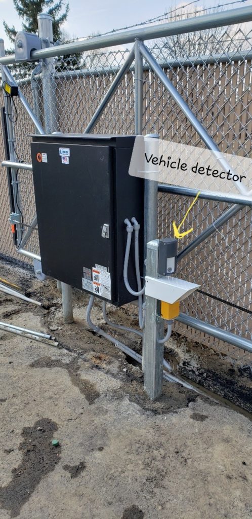 A sliding automated gate operator with a photo eye and a vehicle detector installed above the photo eye