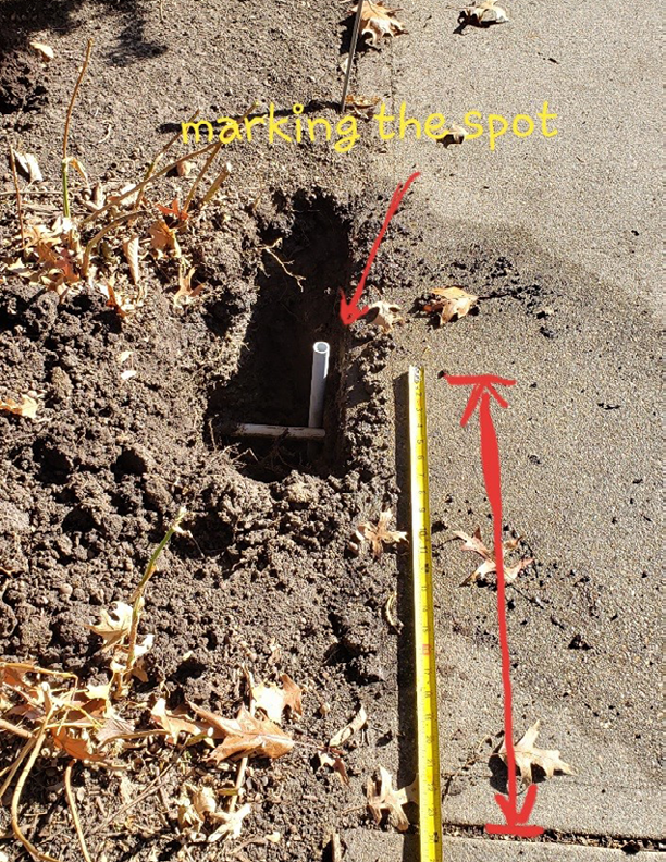 A tap measure resting on the ground compared to a specific marker to mark where exactly the conduits are installed in the ground